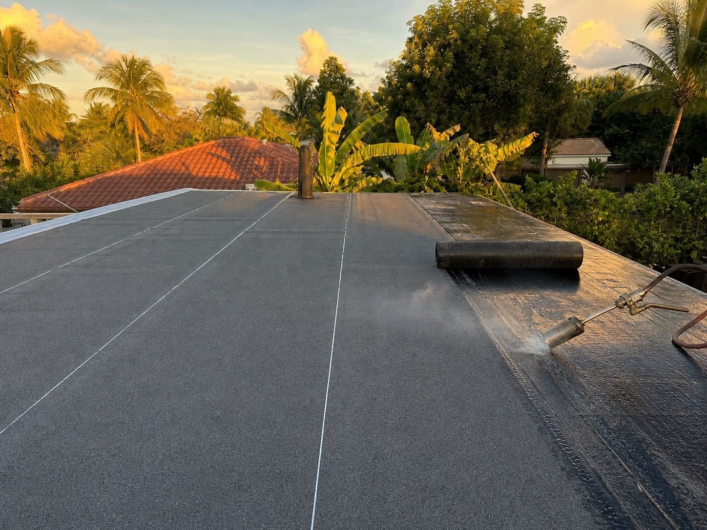 Modified bitumen roofing being rolled out across a low-slope roof