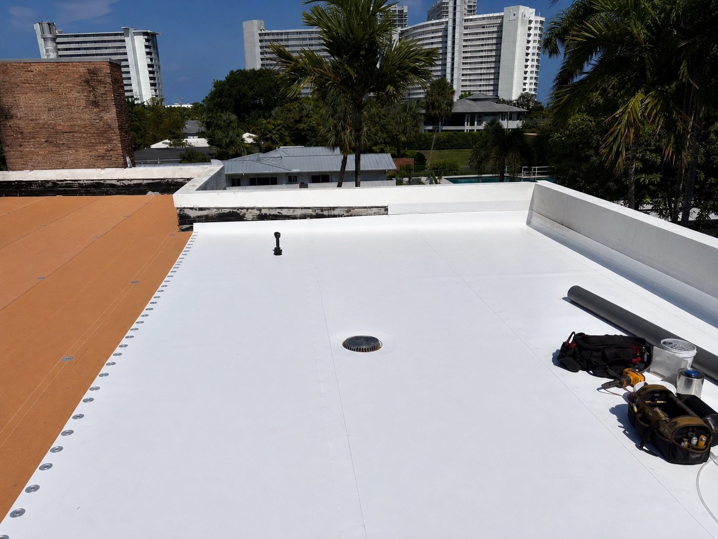 White TPO membrane being installed across a low-slope roof section